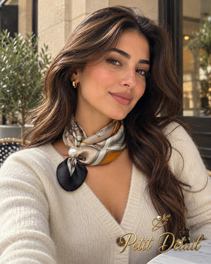Woman wearing camel, ivory and orange equestrian magnetic scarf with pearl magnetic closure