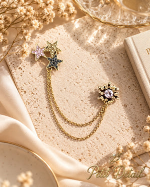 Celestial crystal star chatelaine brooch with floral crystal pin and double gold-tone chains styled on a warm neutral background