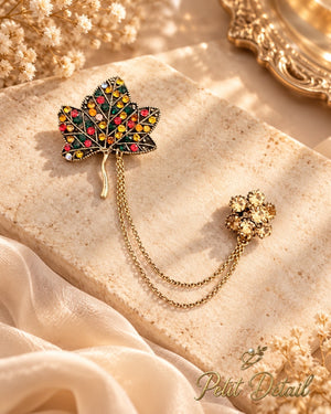 Multicolor crystal maple leaf chatelaine brooch with double chains styled on a warm neutral background