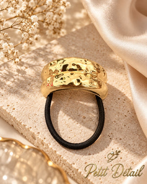 Hammered gold hair cuff with black elastic on beige stone and ivory satin