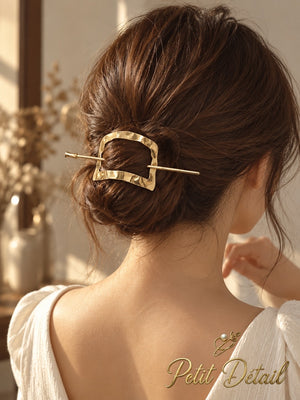 Woman wearing hammered square gold-tone hair cuff secured with matching stick over a low bun