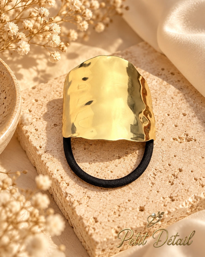 Wide hammered gold-tone hair cuff with black elastic on white background, 5 x 4.5 cm