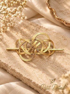 Polished gold interwoven loop hair cuff and matching stick styled on beige stone and satin