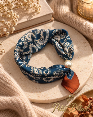 Navy paisley magnetic scarf with pearl magnetic closure styled on a warm neutral background