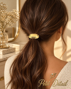 Woman wearing oval ribbed gold-tone hair cuff on low brown ponytail