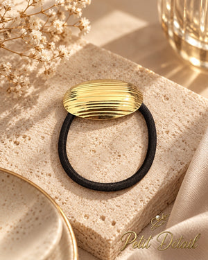 Oval ribbed gold-tone hair cuff with black elastic styled on cream stone with ivory flowers