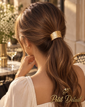 Woman wearing a ripple textured gold-tone hair cuff around a low brown ponytail