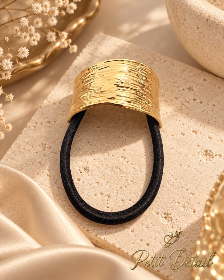 Ripple textured gold-tone hair cuff with black elastic on white background, 4.5 x 2.5 cm