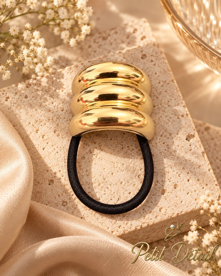 Rounded triple-ridge gold-tone hair cuff with black elastic on white background, 4 x 3.5 cm