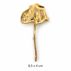 Polished gold-tone ginkgo leaf brooch with a textured fan-shaped leaf and long curved stem on white background, 8.5 × 4 cm