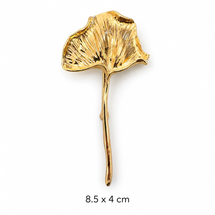 Polished gold-tone ginkgo leaf brooch with a textured fan-shaped leaf and long curved stem on white background, 8.5 × 4 cm