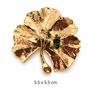 Sculptural hammered gold-tone fan leaf brooch with a cluster of dark green stones on white background, 5.5 × 5.5 cm