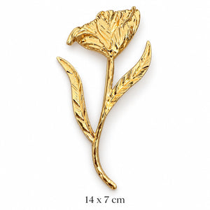 Sculpted gold-tone open bloom brooch with textured flower, two veined leaves and flowing long stem on white background, 14 × 7 cm