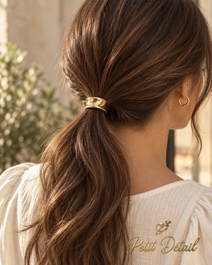 Woman wearing small hourglass gold-tone hair cuff on a low brown ponytail