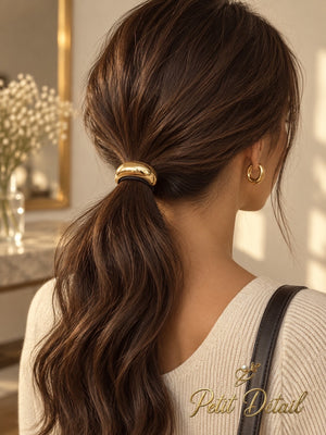 Woman wearing smooth domed gold-tone hair cuff around a low brown ponytail