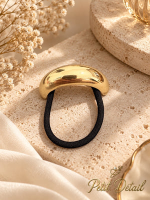 Smooth polished gold-tone hair cuff with black elastic styled on beige stone with ivory flowers and satin