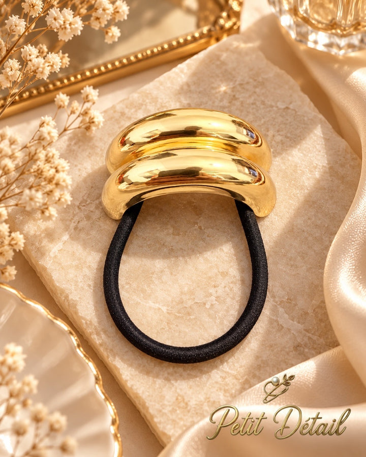 Smooth polished gold-tone double-dome hair cuff with black elastic on white background, 5.5 x 2.5 cm