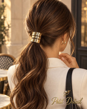 Woman wearing a polished triple-band gold hair cuff around her low brown ponytail