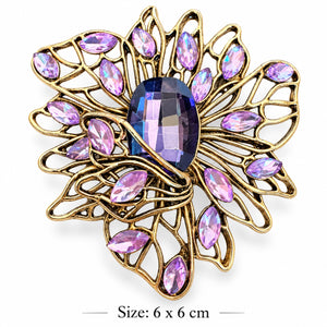 Gold-tone openwork filigree flower brooch with a large faceted violet center and lavender marquise-shaped stones on a white background, 6 × 6 cm