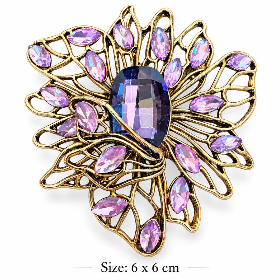 Gold-tone openwork filigree flower brooch with a large faceted violet center and lavender marquise-shaped stones on a white background, 6 × 6 cm